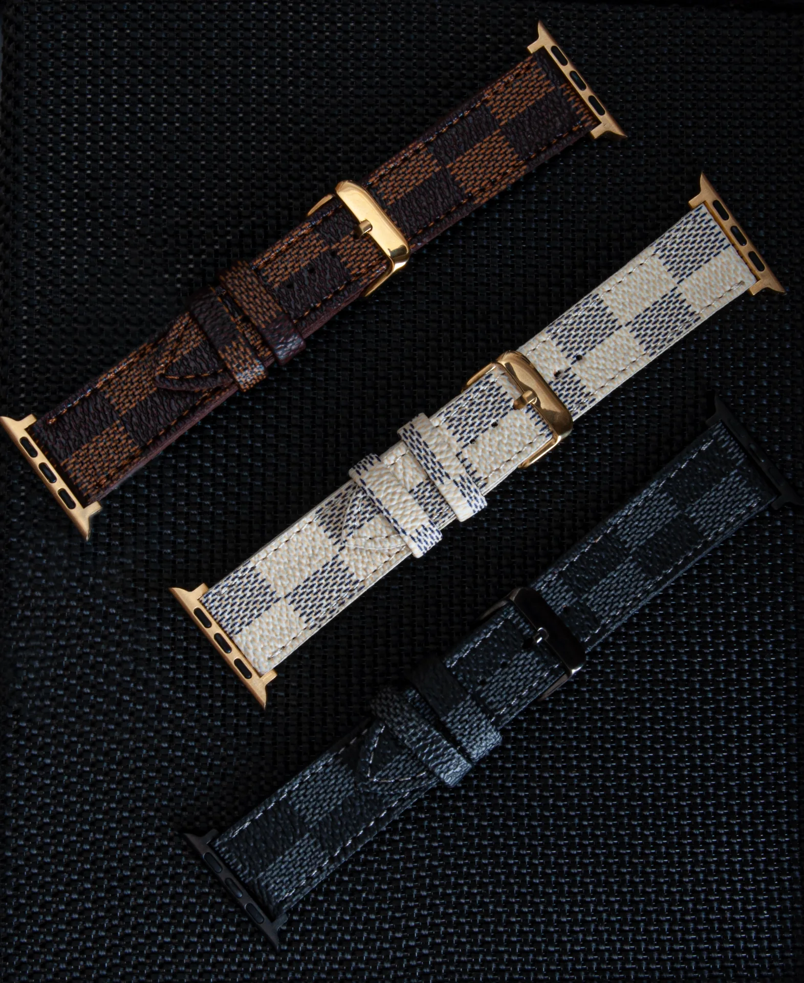 Brown, white and dark leather watch straps arranged diagonally on black.