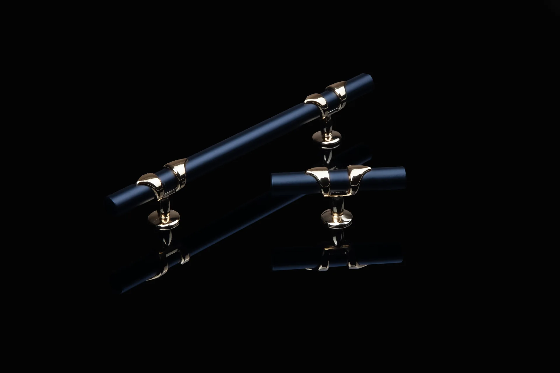Metal cabinet handles and fittings reflected on a black surface.
