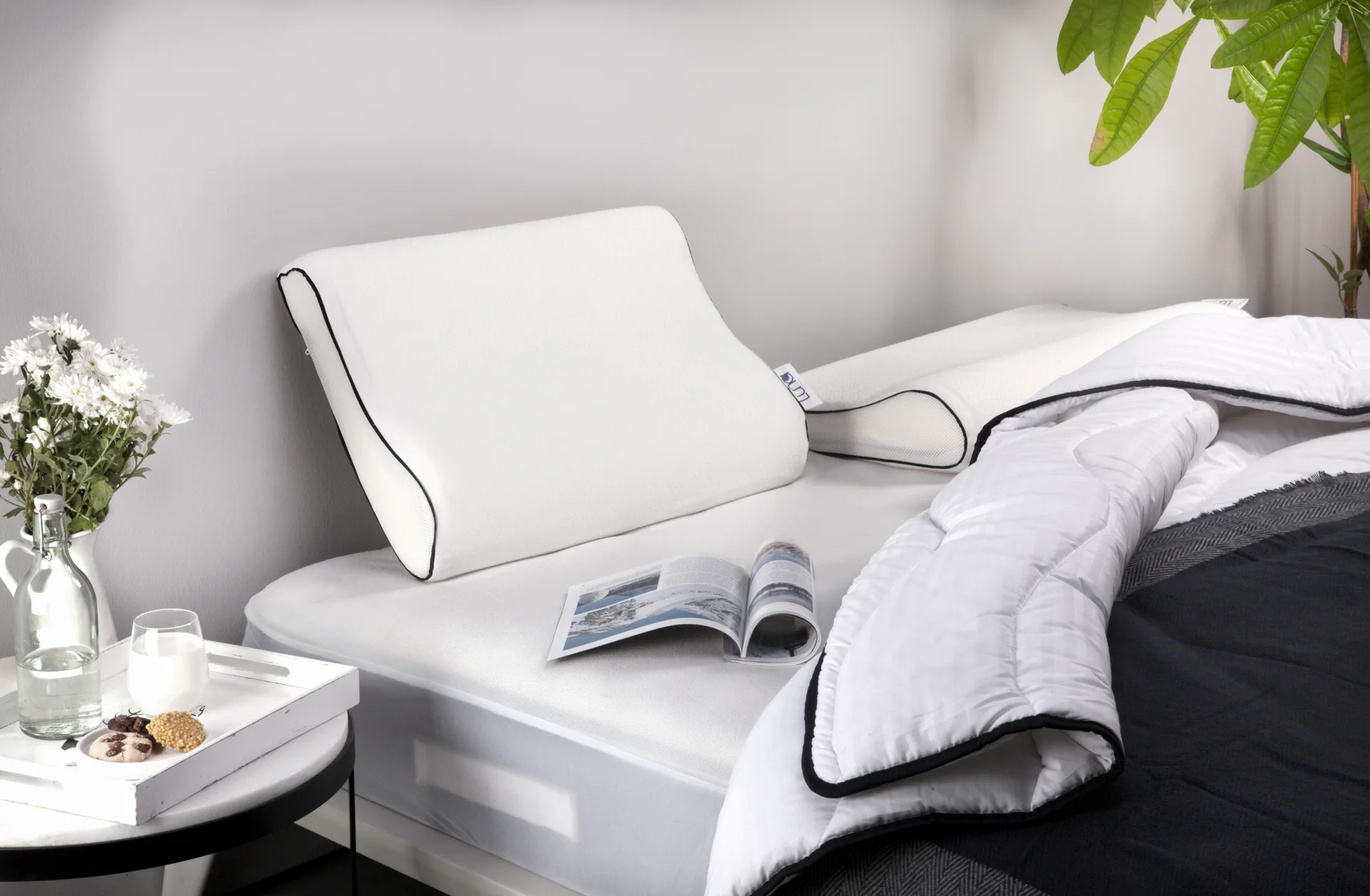 White bedding and pillows styled with an open book and flowers.